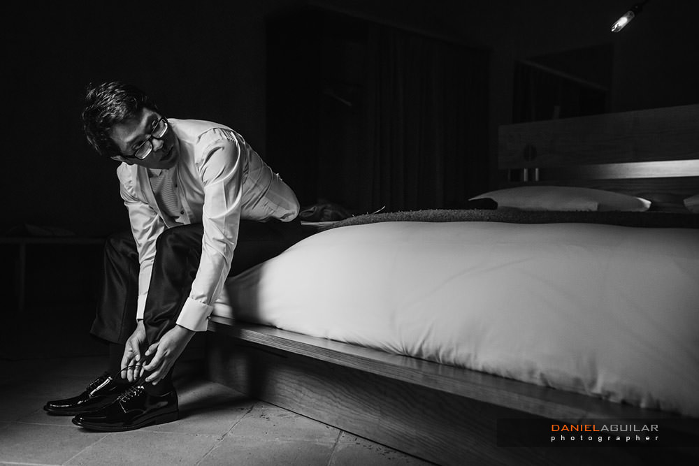 groom tying up his shoes in hotel room