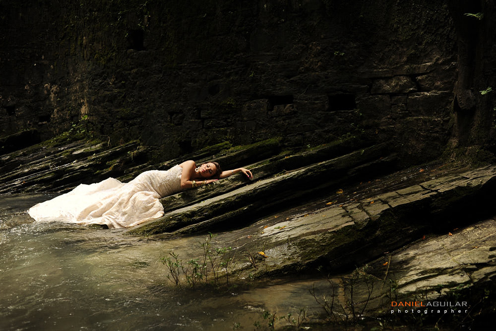 bride laying in the ground at the edge of a river in Xilitla trash the dress